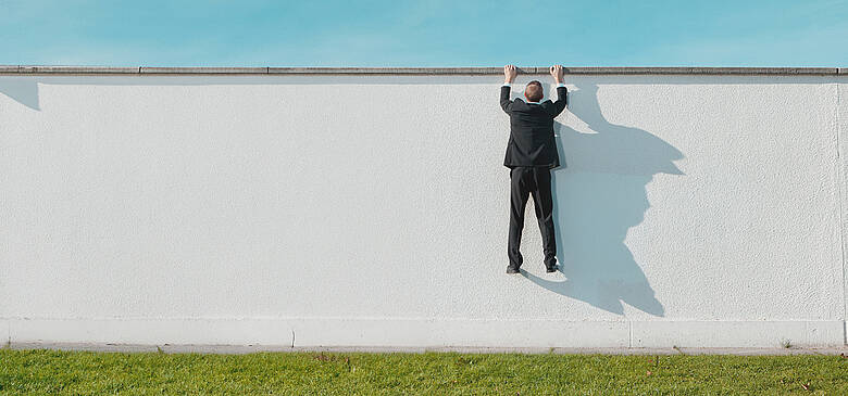 Geschäftsmann Klettern über Mauer