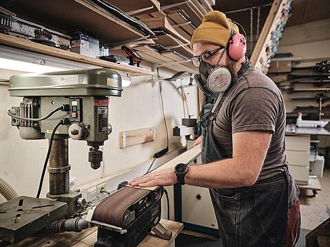 Bild von xelware: Handwerker mit Mundschutz bei der Arbeit an einer Schleifmaschine