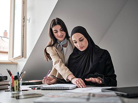 Bild von xelware: Zwei Frauen am Schreibtisch, die zusammen in Unterlagen schauen