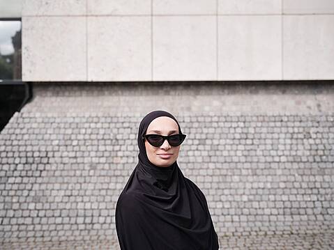 Bild von xelware: Frau mit schwarzem Kopftuch und Sonnenbrille schaut lächelnd in die Kamera